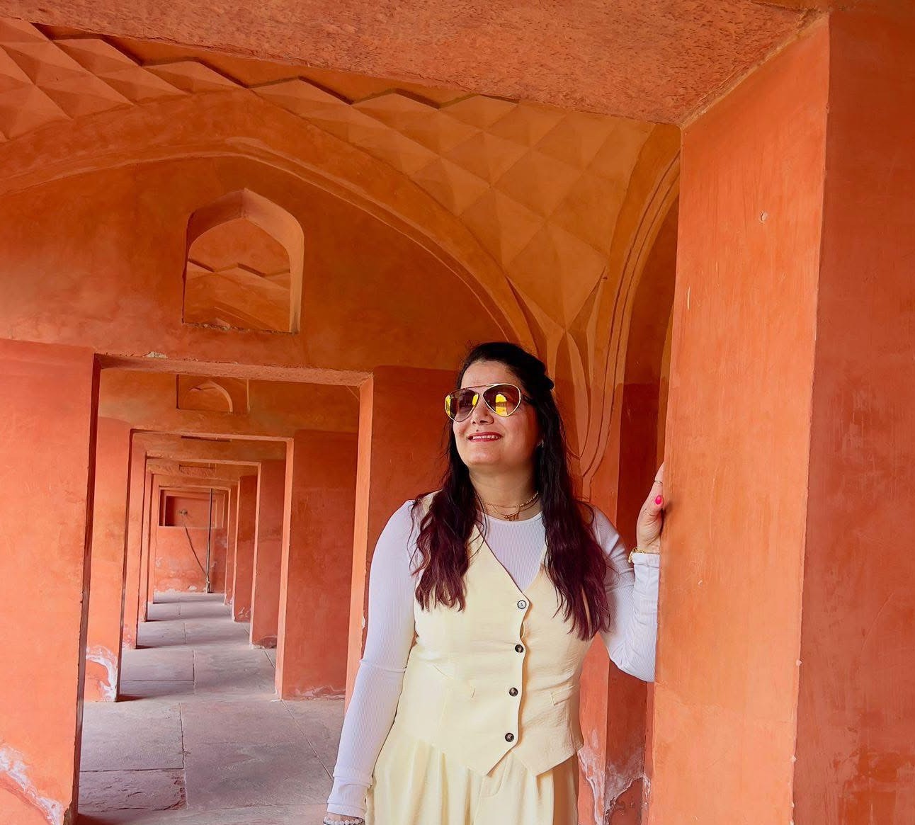Kiran, founder of Rooted Liberation, standing in a sunlit terracotta archway